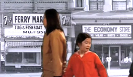 An adult with long dark hair and mustard yellow coat is holding the hand of a child with pigtails, wearing a red coat, looking back. They are superimposed against a black-and-white photo of storefronts with signs: 7up, Ferry [Market], Tug & Fishboat, The Economy Store.